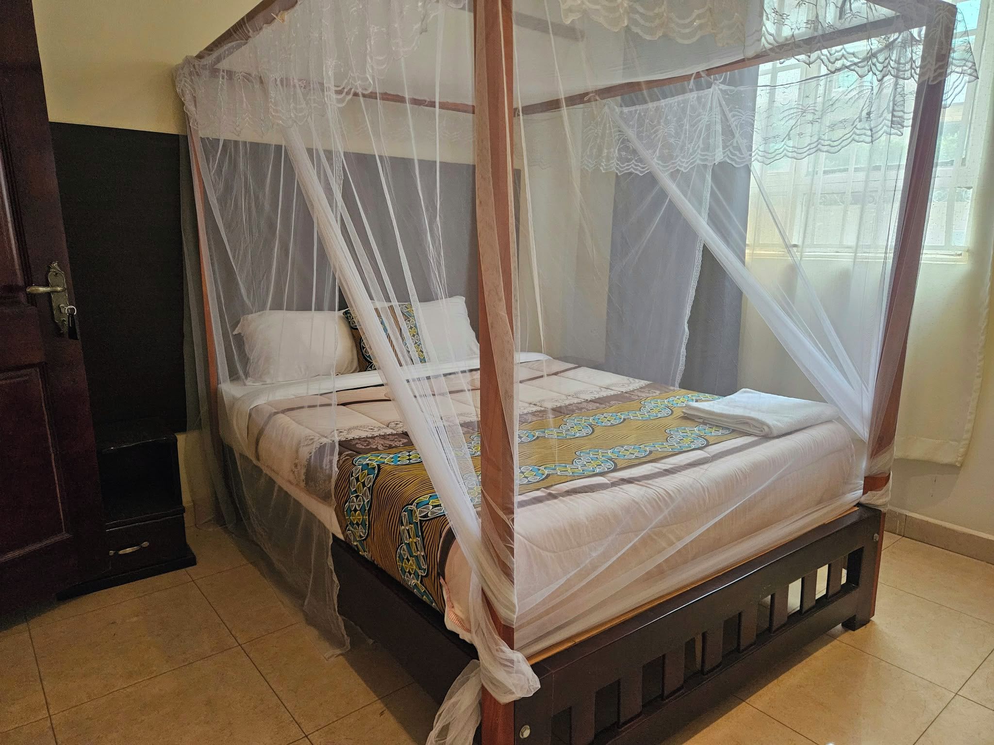 A four-poster bed with a canopy, a bedside table, and a wall-mounted TV.