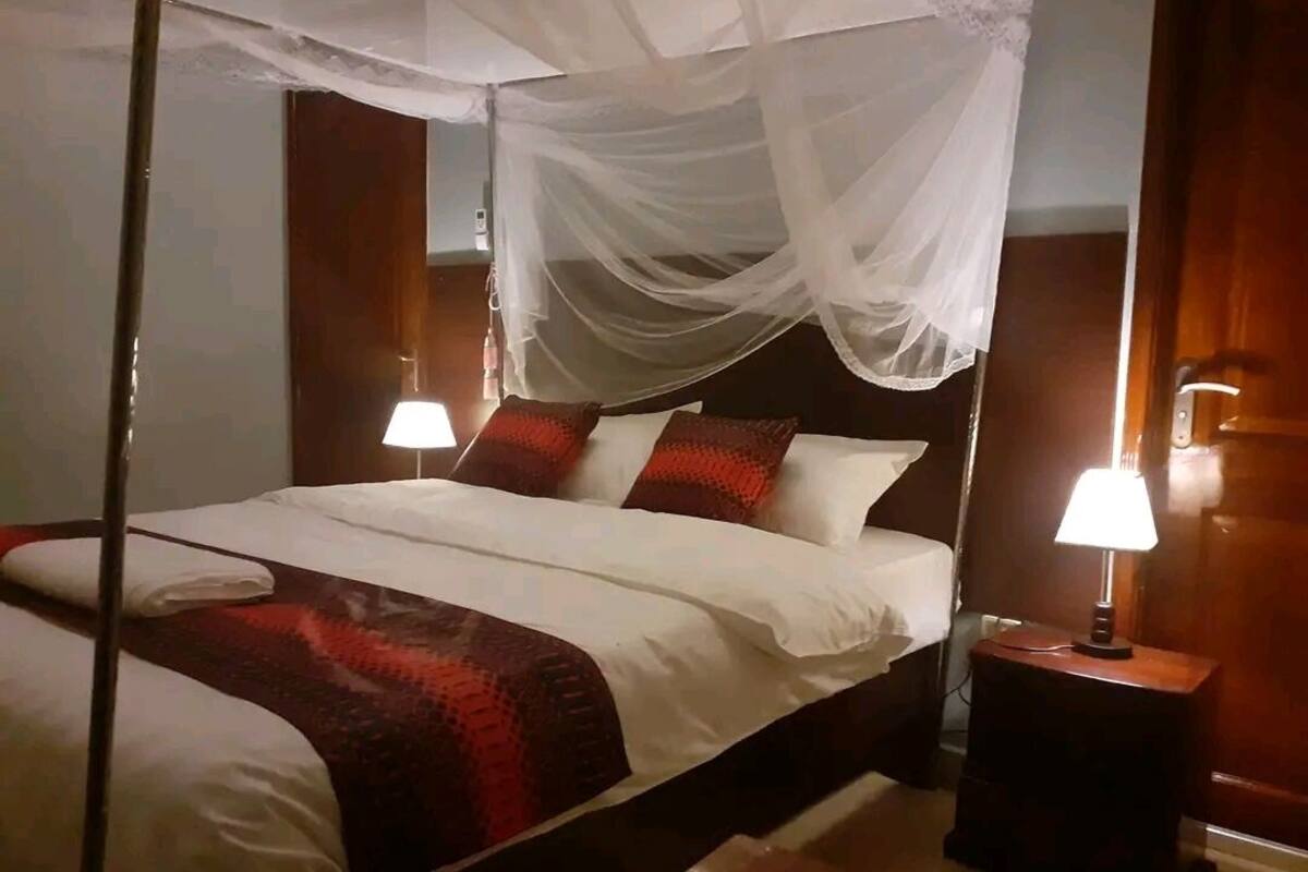 A bed with a canopy, two bedside lamps, and a nightstand.