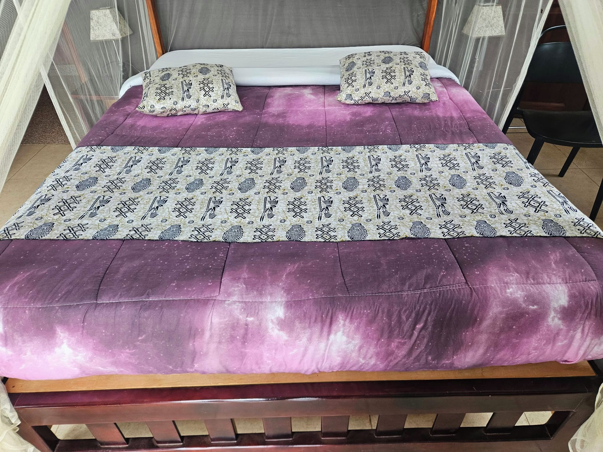 A bed with a purple bedspread and two pillows with a patterned design.