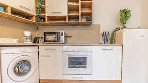 Cocina compacta con lavadora, microondas, horno y refrigerador.