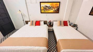 A hotel room with two beds, a painting on the wall, a potted plant, and a tiled floor.