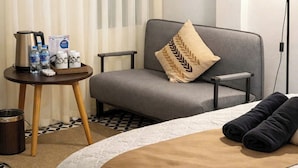 Ein Hotelzimmer mit Bett, einer Sitzecke, einem kleinen Tisch mit Annehmlichkeiten, einer Lampe und einem Bild an der Wand.