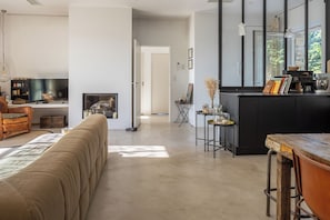 Ein großzügiger Wohnbereich mit Sofa, Kamin, einer Küche mit großer Kochinsel und einem Esstisch.