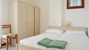 Ein Schlafzimmer mit einem Bett, einem Kleiderschrank, einem Sessel und einem Fenster.