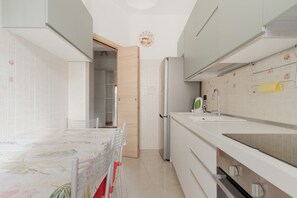 A modern kitchen with white cabinets, a sink, and a dining area with a table and chairs. - GuestHost - Elegant 70mq apartment for 4 people located on the second floor of a typical Milanese building with lift.The accommodation is located in the De Angeli district, located to the west of the historic center and represented by a quiet atmospher (Milan)