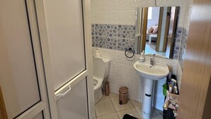 Een badkamer met toilet, wastafel en spiegel.