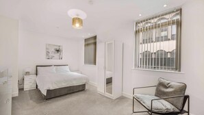 Une chambre à coucher avec un lit, une chaise, une armoire, un miroir et une fenêtre.