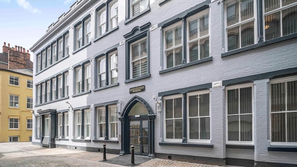 Un immeuble à étages, de style architectural classique, qui se distingue par une entrée en arc de cercle bien visible et de nombreuses fenêtres.