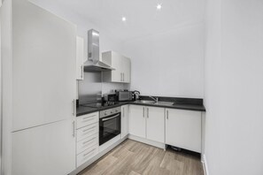 A modern kitchen with white cabinets, a built-in oven, a microwave, and a sink. - Guestready - Gladstone (Liverpool)