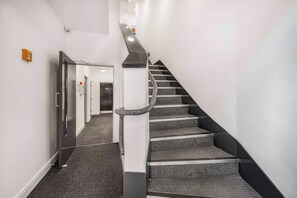 A staircase with a handrail, carpeted steps, and a door at the bottom leading to a hallway. - Guestready - Gladstone (Liverpool)