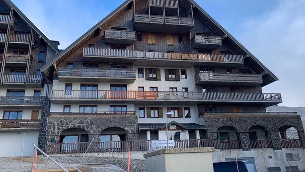 Een hotel met meerdere verdiepingen, balkons, stenen bogen en een heldere lucht.
