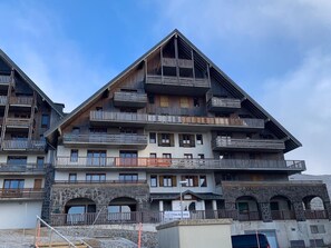 Ein mehrstöckiges Hotel mit Balkonen, steinernen Bögen und blauem Himmel.