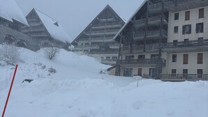 Een met sneeuw bedekte straat met gebouwen met balkons en een bord waarop een hotel wordt aangeduid.