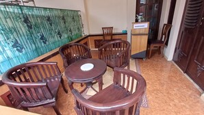 A dining area with wooden furniture and a green decorative wall. - Irma Guest House (Malang)