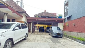 A residential area with a paved driveway, parked cars, and houses with tiled roofs. - Irma Guest House (Malang)