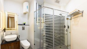 A modern bathroom with a glass-enclosed shower, a white sink, and a toilet.