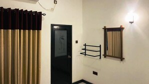 Une pièce avec une porte noire, un appareil de climatisation, un luminaire et un rideau.