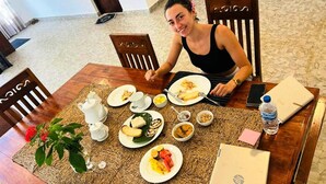 Une table à manger avec des assiettes remplies de nourriture, un ordinateur portable et une bouteille d’eau.