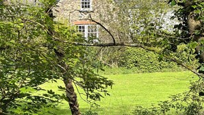 A stone house with a traditional design, surrounded by lush greenery and a well-maintained lawn.