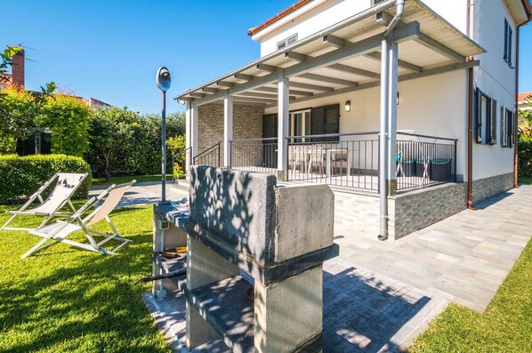 A covered outdoor area with a patio, lounge chairs, and a stone bench. - Villa Sara, a wonderful modern villa with 8 beds and a garden (Piane Vecchie)