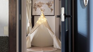 Une pièce avec un plafond en bois, un lit doté d’une tête de lit blanche, une carte du monde accrochée au mur et une tente illuminée.
