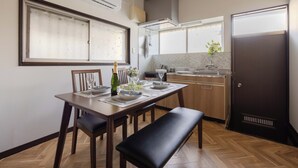 A modern kitchen with wooden cabinets, a dining table set for four, and a bench. - Stopover Between Tokyo&Osaka/ Traditional House/ Live Like a Local/ King Bed (Fudabacho, Hiratsukashi)