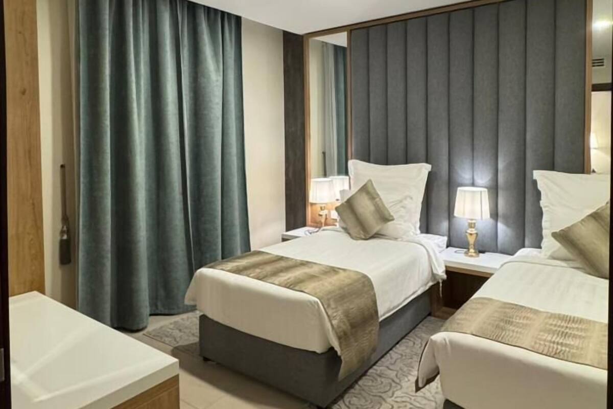 Una habitación de hotel moderna con dos camas, un escritorio de madera y un baño.