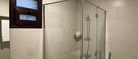 A modern bathroom with a glass-enclosed shower, a marble sink, and a toilet.