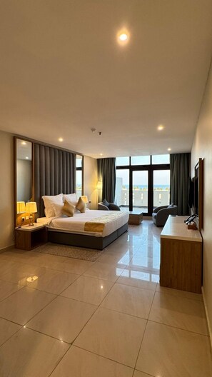 Ein modernes Hotelzimmer mit einem großen Bett, einem Schreibtisch und Blick auf die Stadt.