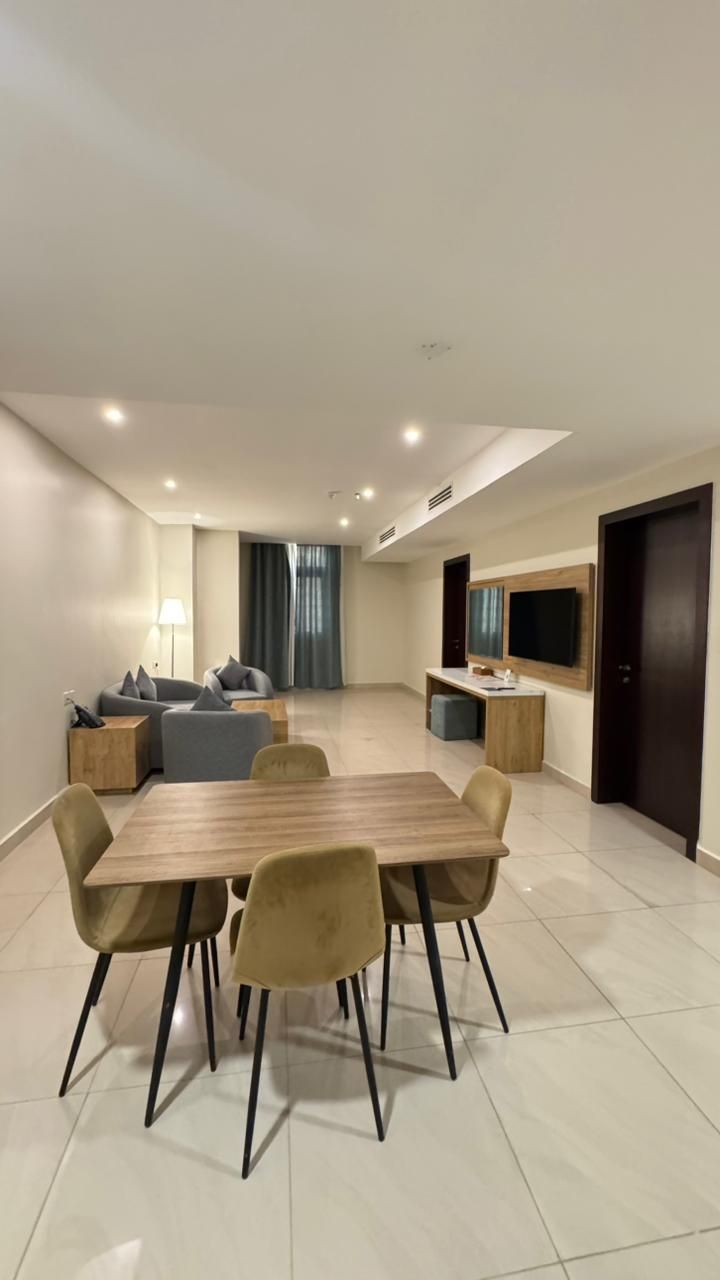 Una sala de estar moderna con comedor, un conjunto de sofás, un televisor y un mueble de madera.
