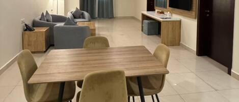 Una sala de estar moderna con comedor, un conjunto de sofás, un televisor y un mueble de madera.
