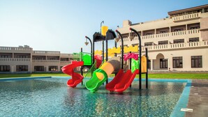 A swimming pool with a water slide and a playground structure. - Continent Hotel Al Uqayr (Al Uqayr)