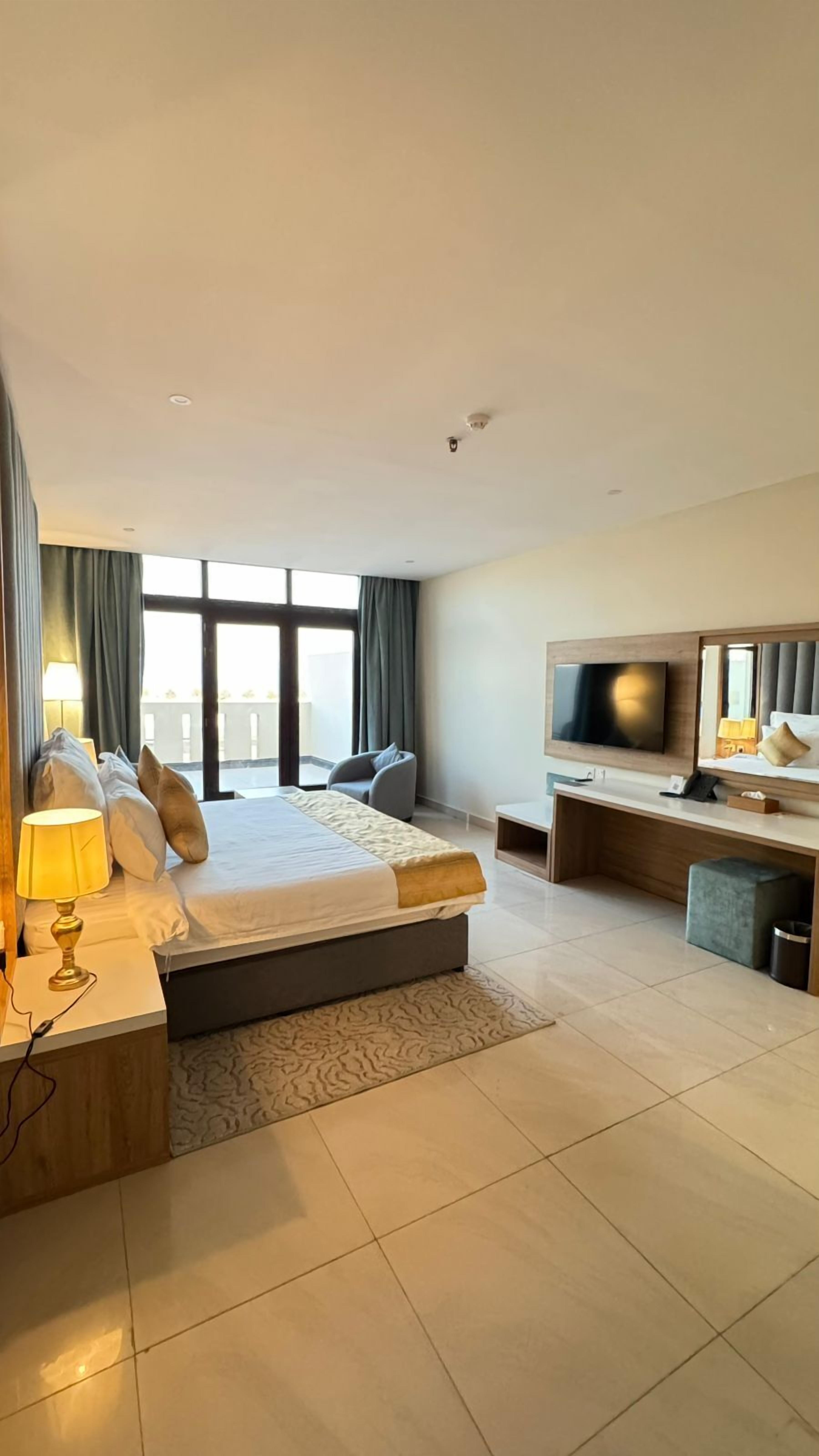Ein modernes Hotelzimmer mit einem großen Bett, Nachttischlampen, einem Fernseher und einem Schreibtisch.