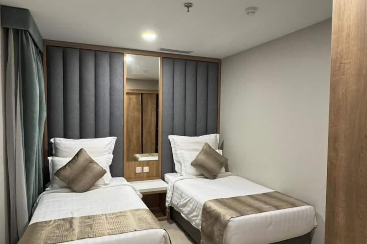 Una habitación de hotel moderna con dos camas, un espejo grande y un armario de madera.