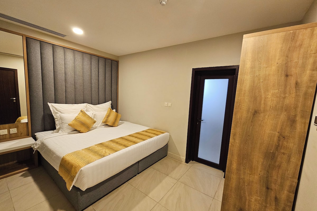 Un dormitorio moderno con una cama grande, un armario de madera y una puerta que da a otra habitación.