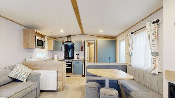 A compact RV kitchen with a central island, a dining area with a bench, and a seating area with ottomans. - Silver 4 Bedroom Holiday Home (Hornsea)