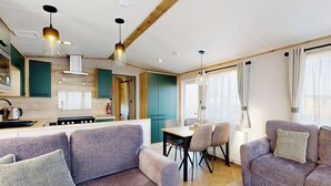 Une cuisine moderne avec des poutres en bois, un coin repas avec une table et des chaises, et un salon avec des canapés.