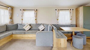 Una habitación moderna y bien iluminada con un sofá seccional gris, un banco de madera y otomanas.