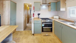Cocina compacta con estufa a gas, horno y una pequeña encimera.