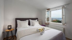 A bedroom with a bed, a nightstand, a window with a view, and a radiator. - Casa Della Cava - Private Villa in Seget Donji (Seget)