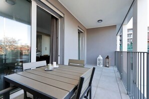 A balcony with a table and chairs, a sliding door, and a view of the city. - Delizioso monolocale con ampio terrazzo a Testaccio (ROMA)