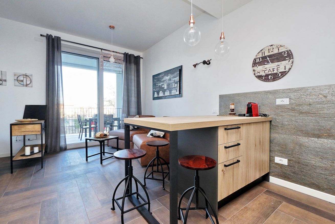 Een moderne keuken met een centraal eiland, barkrukken en een zithoek met een bank en stoelen.