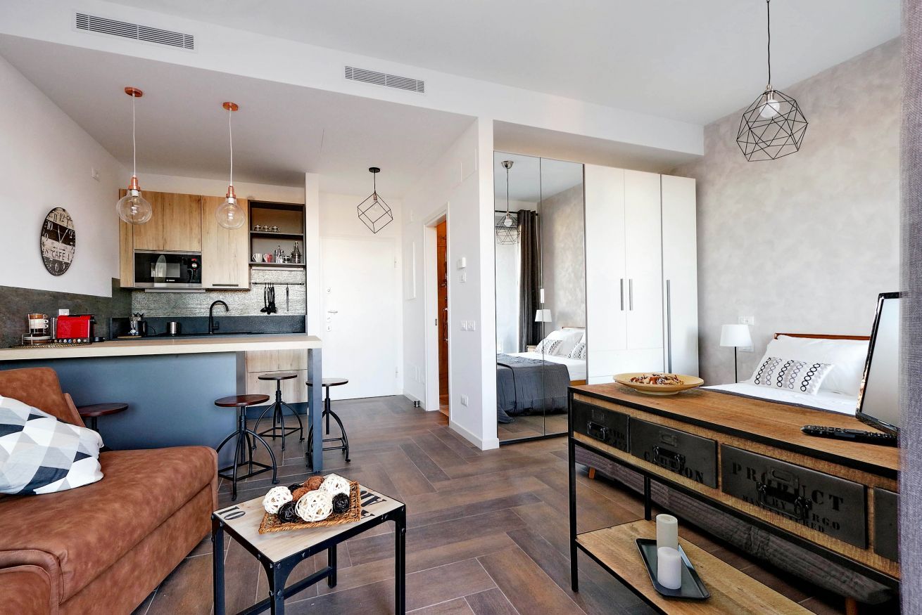 Een moderne woonruimte met keuken, eethoek en slaapkamer.