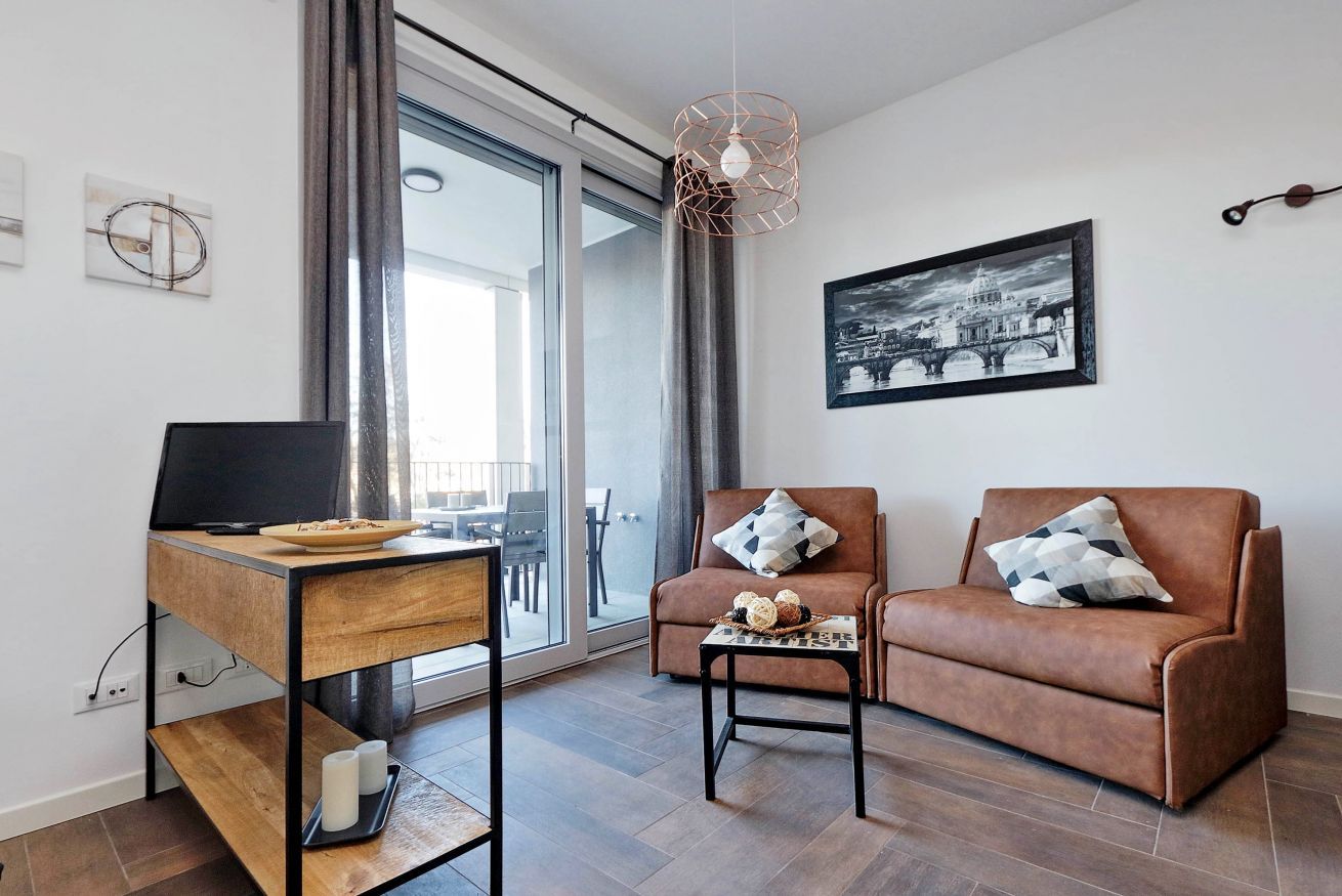 A modern living room with a sofa, a coffee table, a TV on a wooden stand, and a large window.