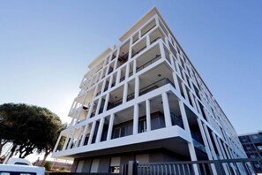 A modern multi-story building with a geometric facade, balconies, and a gated entrance. - Delizioso monolocale con ampio terrazzo a Testaccio (ROMA)