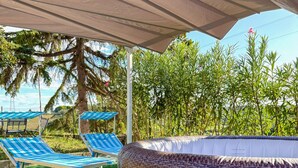 A covered outdoor area with a large wicker hot tub, two blue and white striped lounge chairs, and artificial green turf. - Mary Jungle - Sant`Elpidio a Mare (Sant` Elpidio a Mare)