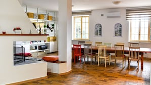 A spacious living area with a wooden floor, a dining table with chairs, and a kitchen area with shelves and a staircase. - Mary Jungle - Sant`Elpidio a Mare (Sant` Elpidio a Mare)