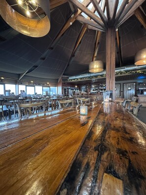 A spacious restaurant with a long wooden bar, high ceilings, and exposed beams. - Chalet Pampus 16 - comfort, plenty of space & large sun terrace for 4 people (Lauwersoog)