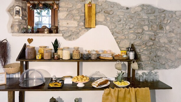 Montaje de bufé con diferentes alimentos, frascos de condimentos y un fondo de pared de piedra.