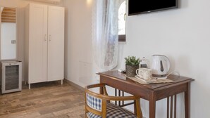 Ein Zimmer mit einem Holztisch, einem Fernseher, einem Schrank und einem kleinen Kühlschrank.